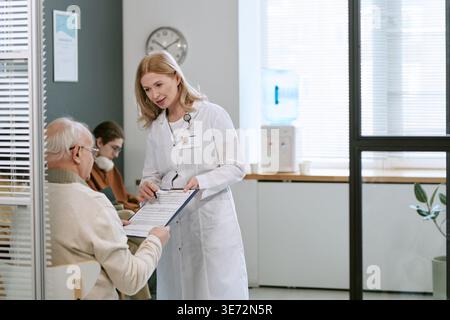 Adult Female Doctor Explaining Medical Form to Senior Man Stock Photo