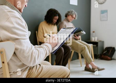 Senior Man Completing Intake Form in Therapy Waiting Room Stock Photo