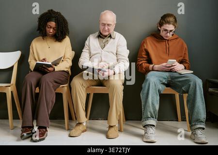 Diverse People Waiting and Using Devices in Modern Clinic Lobby Stock Photo