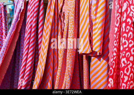 Vibrant patterned textiles like stripes and animal print displaying at an outdoor market Stock Photo