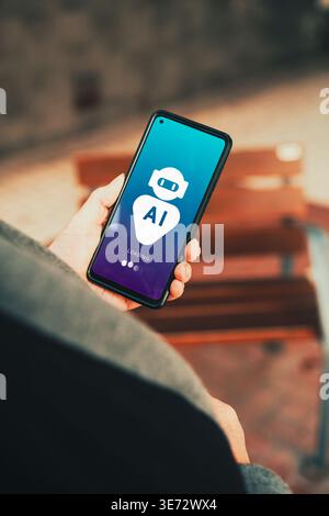 AI chatbot app loading on smartphone screen held by person outdoors. Digital transformation with Artificial Intelligence. Stock Photo