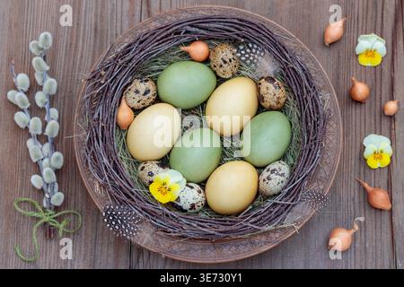 naturally dyed Easter eggs and quail eggs on a wooden plate Stock Photo