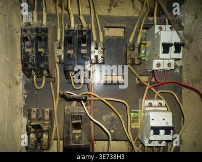 Vintage electrical circuit breakers and various components are displayed on a metal panel. Dim lighting creates an industrial atmosphere, emphasizing Stock Photo