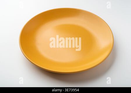 Yellow ceramic plate on a white table. Stock Photo