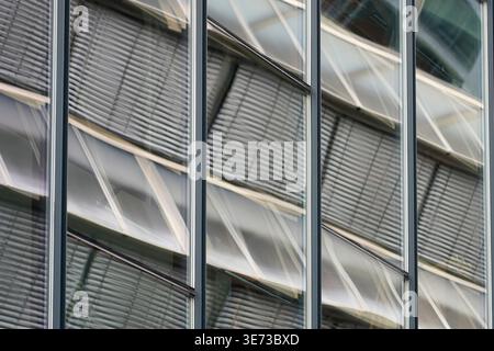 Modern glass facade with repeating window panels and blinds reflecting structural lines in Oslo, Norway Stock Photo
