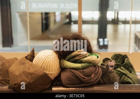 England, London, Southwark, Tate Modern, Rear view of Loving Couple Sitting on Sofa Wearing Winter Clothing Stock Photo