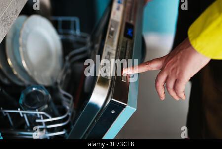 Woman finger pressing Eco button on dishwasher panel. Stock Photo