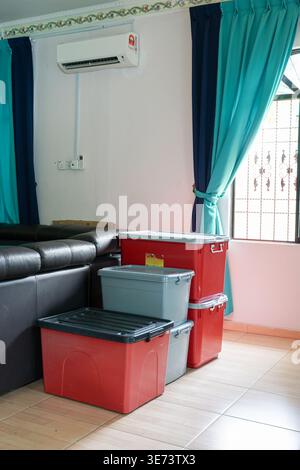 Stack of plastic storage boxes in a bright modern living room. Stock Photo
