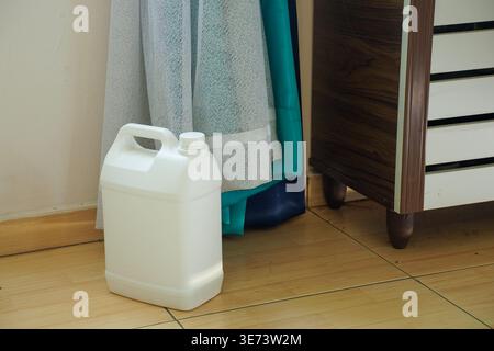 A blank white plastic gallon container sitting on a tiled floor indoor Stock Photo
