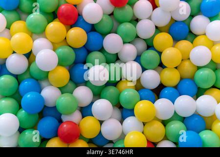 A ball pit filled with numerous multicolored plastic balls. Childhood, recreation, early education, and sensory play environments concept. Stock Photo
