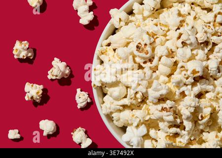 Overhead view of bowl of popcorn on red background Stock Photo