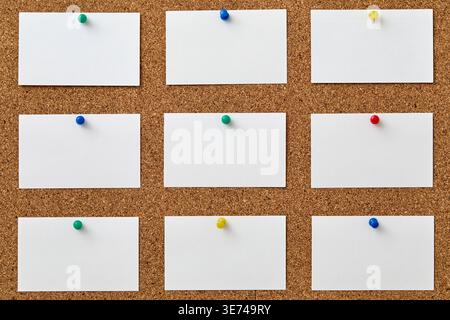 Blank pieces of paper attached to cork board with colorful push pins Stock Photo