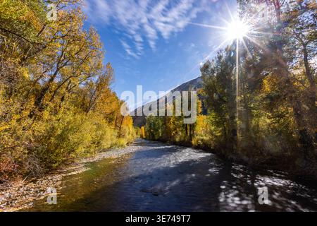 USA, Idaho, Hailey, Big Wood River and sun shining through trees with fall foliage Stock Photo