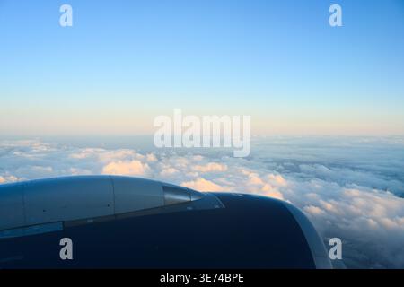 Blue sky and horizon with white cloud tops beyond large aircraft engine Stock Photo