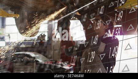 Grinding mechanic using angle grinder under lift in garage, gloves sparks, data overlay, copy space. Undercarriage, workshop, grind, arcs, daylight, i Stock Photo