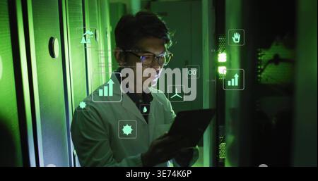 Monitoring technician in lab coat and glasses holding tablet among server racks, data overlays. Engineer, telemetry, ambient, cabinets, cables, ventil Stock Photo