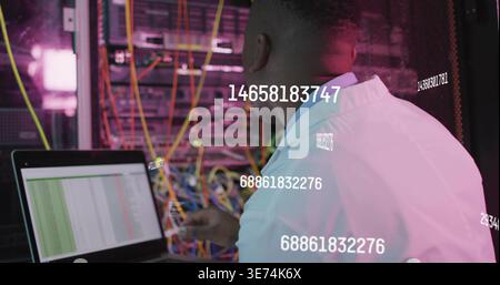 Inspecting tech in coat monitoring rack with cables, laptop, LEDs, data overlays, copy space. Datacenter, server, cabling, technician, jacket, neon, m Stock Photo