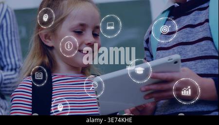Watching girl in red white blue striped shirt focusing on tablet in classroom, with AR icons. Student, collaboration, device, learning, education, dig Stock Photo