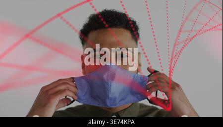 Adjusting male lifting blue purple mask in studio, wearing olive green shirt, with red dotted arcs. Facecover, interior, projection, graphics, headsho Stock Photo