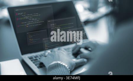 Software developer working on laptop with code overlay.Programmer hands typing on computer keyboard in dark office.Digital transformation and software Stock Photo