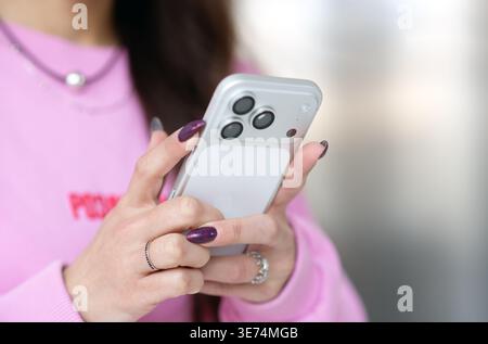 Kyiv, Ukraine. March 20, 2026. Woman using smartphone Apple iPhone 17 in pink sweater, close up of hands with modern device and mobile communication c Stock Photo