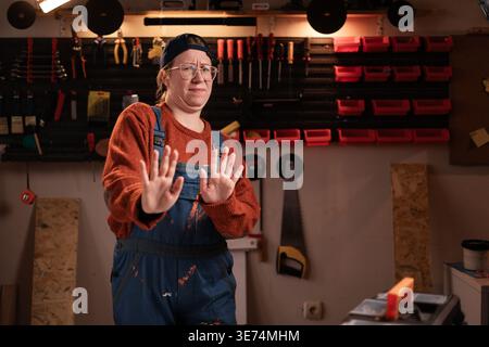No thanks. Carpenter woman rejecting shake hands to decline offer looking at camera working in her carpentry workshop. copy space Stock Photo