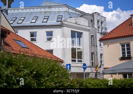 A street view of the Lithuanian National Drama Theatre in Vilnius, featuring a distinctive white building with a metallic roof and multiple Stock Photo