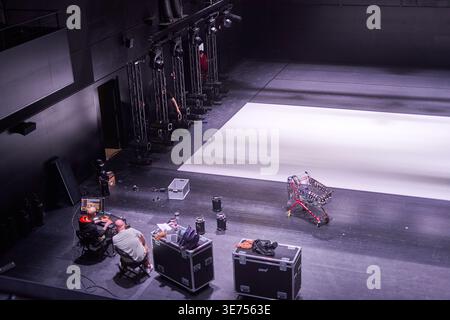 High-angle view of a modern theater or performance venue interior during technical setup. Two technicians operate computer equipment at a desk in the Stock Photo