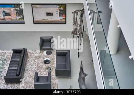 Aerial view of a contemporary minimalist interior space featuring modern black leather furniture arranged on a textured light-colored area rug. The Stock Photo