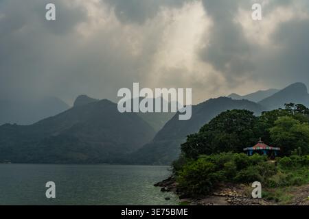 Dramatic sun rays breaking through dark storm clouds over a mountain lake Stock Photo