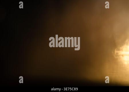 Dark abstract background with warm grainy light bokeh and particle texture Stock Photo