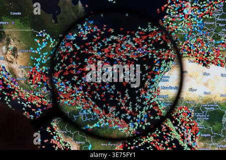 Digital world map under a magnifying glass showing global AIS vessel tracking and high-density shipping traffic across the Atlantic Ocean, North Stock Photo