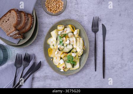 Top view of pickled zucchini salad with feta pine nuts basil and bread slices on gray table Stock Photo