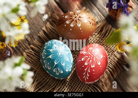Colorful Easter eggs decorated with wax on a wooden table with cherry blossoms Stock Photo