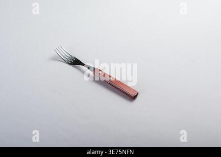 Fork isolated on white backdrop. Studio shot showcases stainless steel, wood grain, and rivet details. Use for food, dining, kitchenware concepts in n Stock Photo