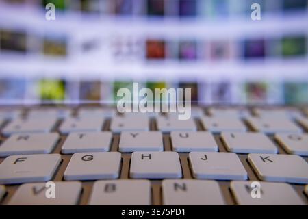 A section of the white keyboard of a laptop against the defocused screen, wide macrophotography. Stock Photo