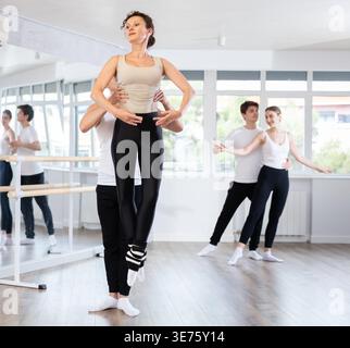 Contemporary ballet dancers couple performing graceful choreography, training entrechat ballet pose in ballet hall Stock Photo