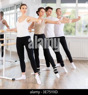 Group of dancers doing batman tandu jete at barre Stock Photo