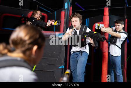 Three people having fun playing lasertag in arena Stock Photo