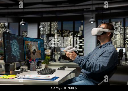 Design specialist using VR glasses and AI on interior design program at the office, moving assets for new apartment floor plan with artificial intelligence ideas in 3D modeling software. Stock Photo