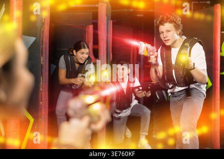 Three people having fun playing lasertag in arena Stock Photo