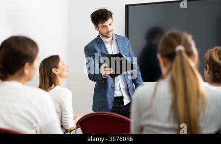 Young male tutor teaching students in college classroom Stock Photo