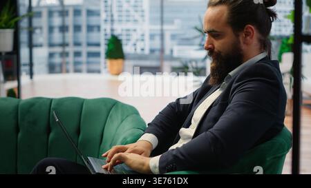 Entrepreneur transferring money online using his credit card and PC, handling financial matters efficiently to achieve success. Male CEO managing all his payments before deadline. Camera B. Stock Photo