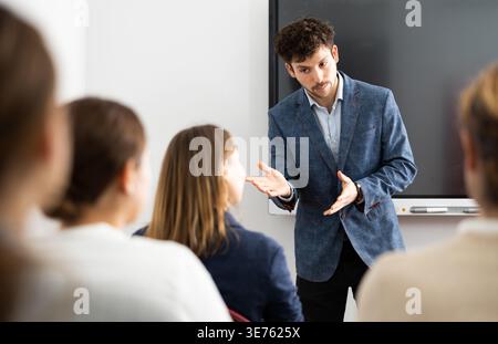 Young male tutor teaching students in college classroom Stock Photo