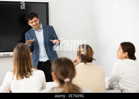Young male tutor teaching students in college classroom Stock Photo