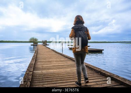 Woman backpacker walking pier on lake azur, france Stock Photo