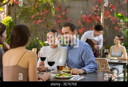 Meeting of two married couples in cozy open-air restaurant Stock Photo