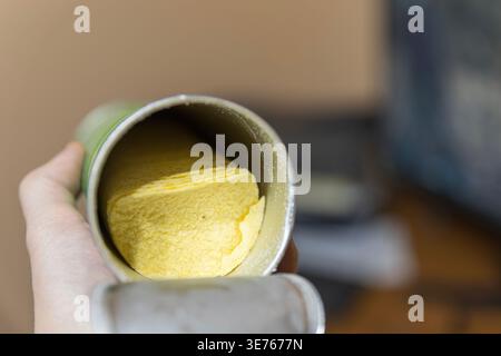 Hand holding open can of stacked potato chips, close-up view Stock Photo