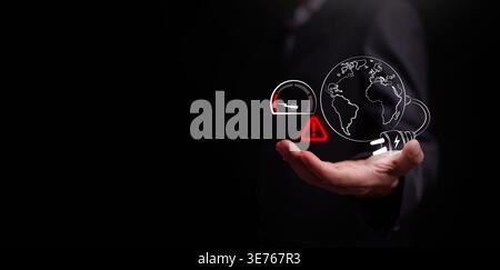 Businessman holding globe with energy gauge and warning sign. Concept of energy crisis, global power consumption limits, electricity and resource scar Stock Photo