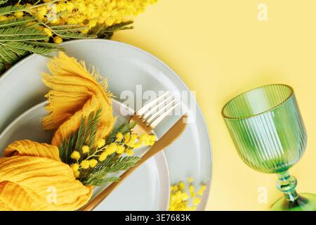 Spring dining composition with mimosa flowers and pastel tableware Stock Photo